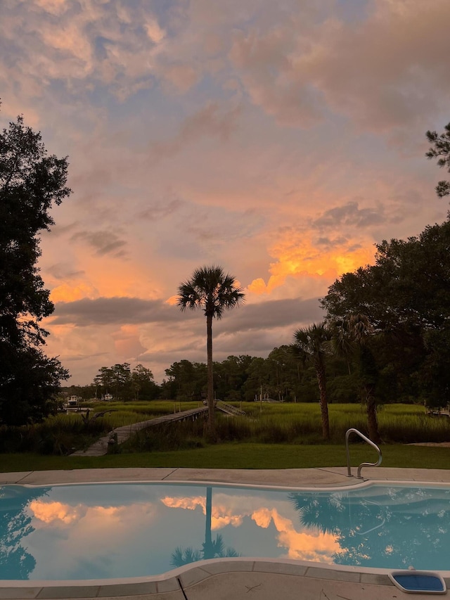 outdoor pool featuring a lawn