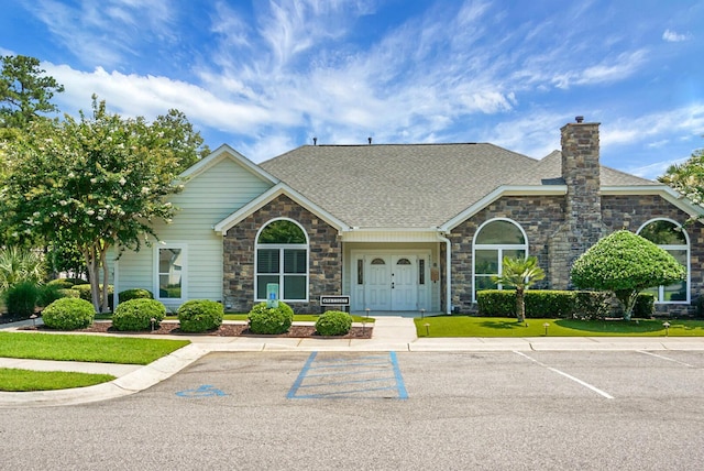 8800 Dorchester Rd Unit 2004, North Charleston, SC 29420 - view of front of home with stone siding, a chimney, uncovered parking, and a shingled roof