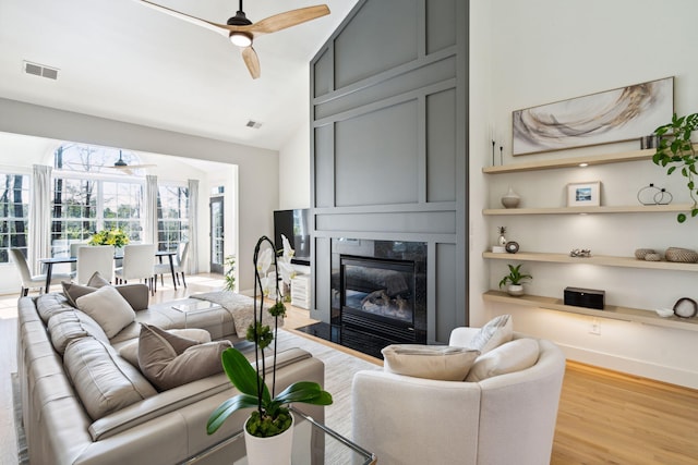 living room featuring ceiling fan, high vaulted ceiling, and light wood-type flooring