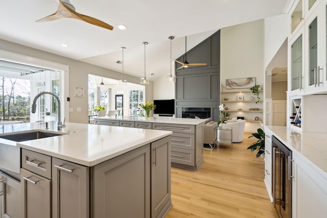 kitchen featuring sink, ceiling fan, a kitchen island with sink, gray cabinetry, and wine cooler