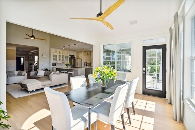 dining space with ceiling fan, lofted ceiling, and light hardwood / wood-style flooring