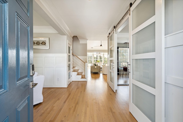 entryway with ornamental molding, a barn door, and light hardwood / wood-style flooring