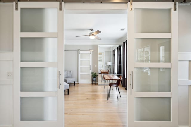 interior space with crown molding, built in shelves, a barn door, and ceiling fan