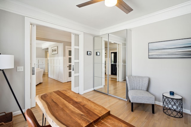 sitting room with ceiling fan, ornamental molding, and light wood-type flooring