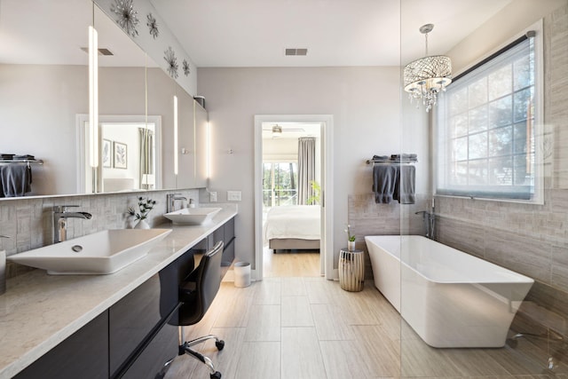 bathroom featuring vanity, a washtub, and tile walls