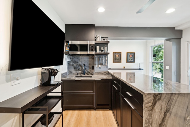 kitchen featuring sink, tasteful backsplash, ceiling fan, light stone countertops, and light hardwood / wood-style floors