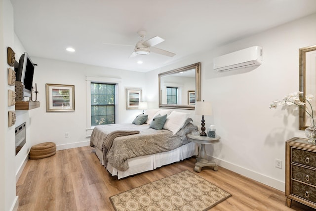 bedroom featuring ceiling fan, a wall mounted AC, and light wood-type flooring