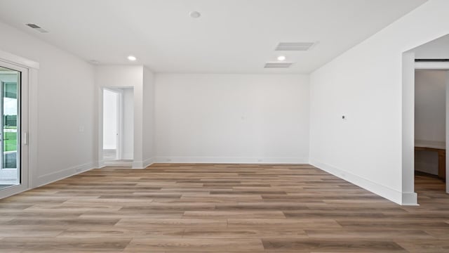 empty room featuring light wood-type flooring, baseboards, and recessed lighting
