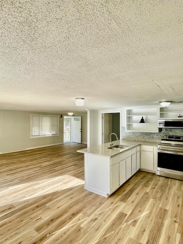 kitchen featuring white cabinetry, light hardwood / wood-style flooring, kitchen peninsula, a textured ceiling, and appliances with stainless steel finishes