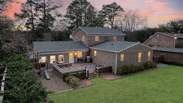 back house at dusk featuring a yard and a deck