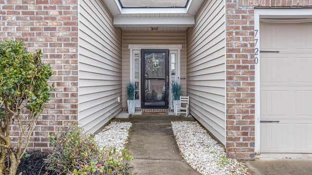 doorway to property featuring a garage and brick siding