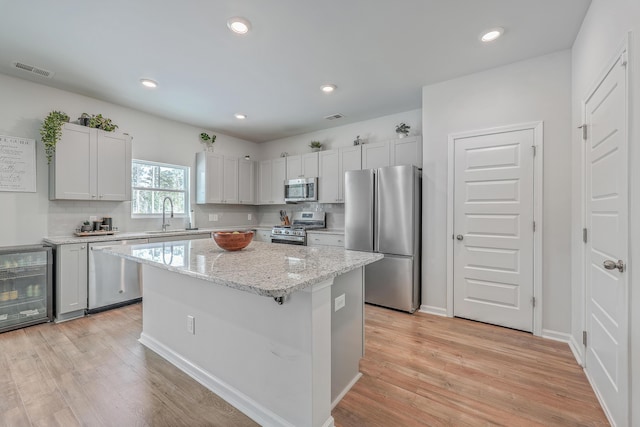 kitchen with sink, light hardwood / wood-style floors, a center island, and appliances with stainless steel finishes