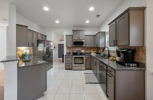 8328 Berringer Blf, North Charleston, SC 29418 - kitchen with stainless steel appliances, a peninsula, dark stone countertops, backsplash, and light tile patterned floors