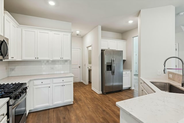 kitchen featuring sink, stainless steel appliances, dark hardwood / wood-style flooring, decorative backsplash, and white cabinets