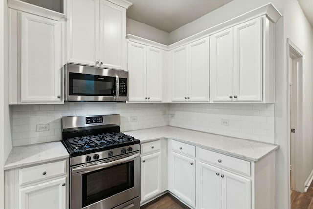 kitchen featuring white cabinets, light stone counters, stainless steel appliances, and dark wood-type flooring