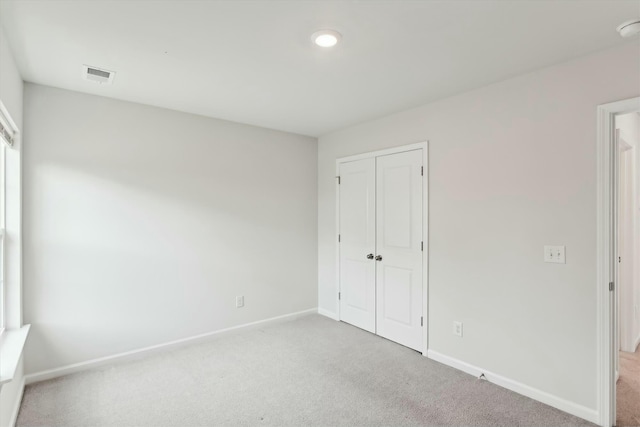 unfurnished bedroom featuring light colored carpet and a closet