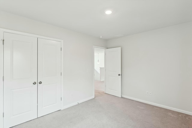 unfurnished bedroom with light carpet and a closet