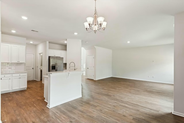 kitchen featuring white cabinetry, light wood-type flooring, stainless steel fridge with ice dispenser, and backsplash