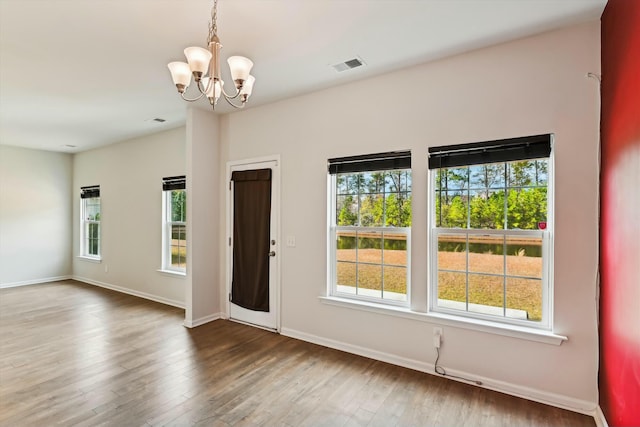 spare room featuring an inviting chandelier and hardwood / wood-style flooring