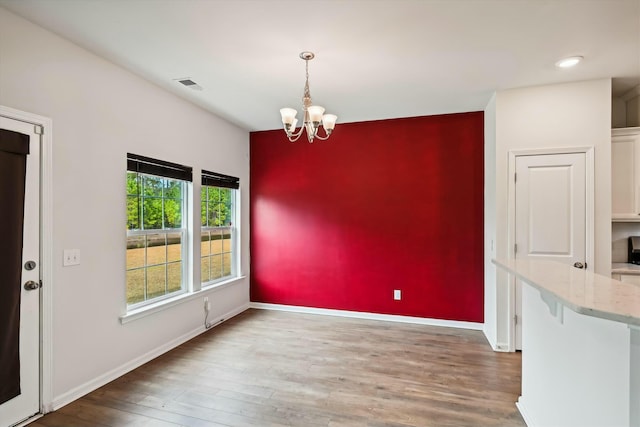 unfurnished dining area with dark hardwood / wood-style flooring and a chandelier