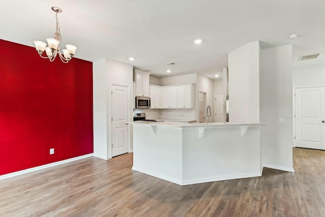 kitchen with white cabinetry, an inviting chandelier, stainless steel appliances, and hardwood / wood-style flooring