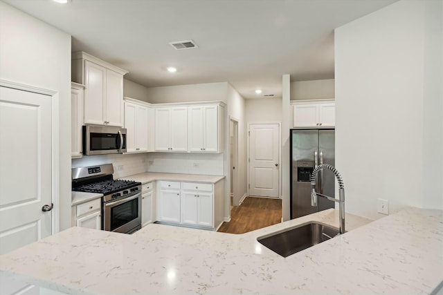 kitchen featuring kitchen peninsula, appliances with stainless steel finishes, dark hardwood / wood-style flooring, sink, and white cabinets