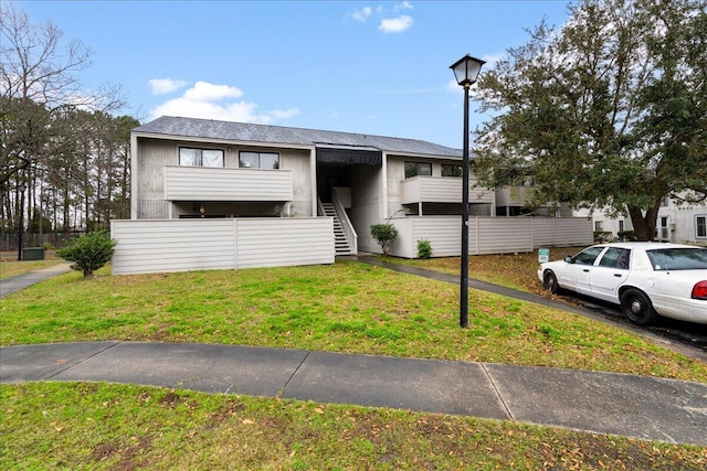 view of front of property featuring stairs and a front yard