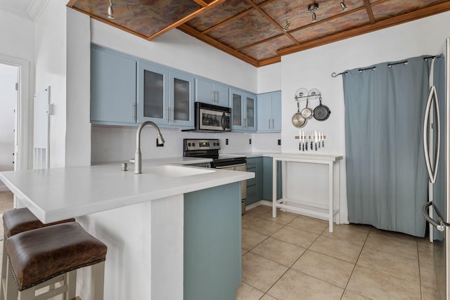 kitchen with stainless steel appliances, blue cabinets, a kitchen bar, and kitchen peninsula