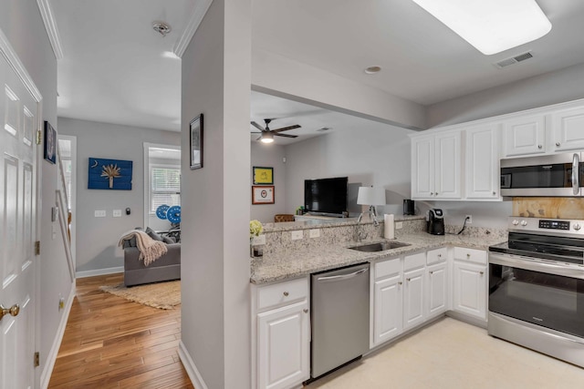 kitchen featuring crown molding, appliances with stainless steel finishes, sink, white cabinets, and light hardwood / wood-style flooring