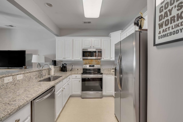 kitchen featuring appliances with stainless steel finishes, sink, light stone counters, and white cabinets