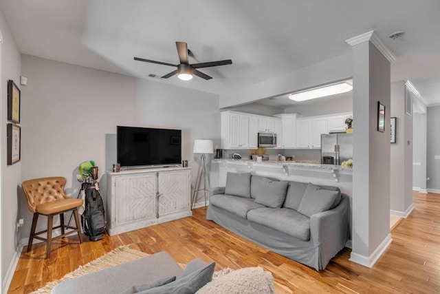 living room featuring ornamental molding, light hardwood / wood-style flooring, and ceiling fan