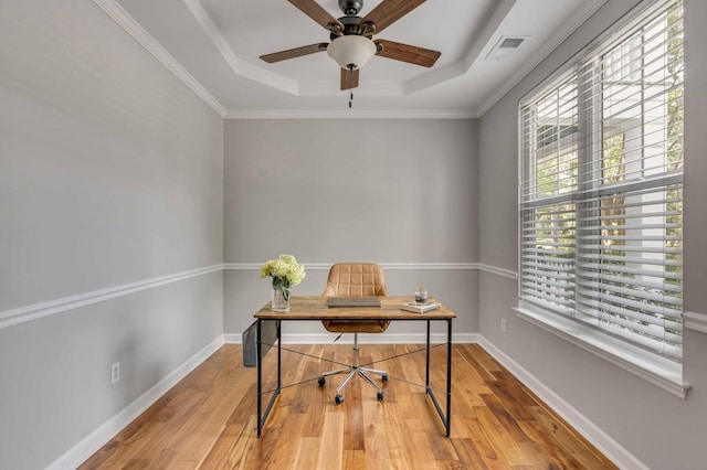 office area with light hardwood / wood-style flooring, crown molding, and a tray ceiling