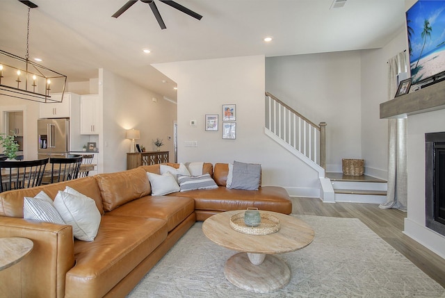 living room with stairs, recessed lighting, wood finished floors, and a fireplace