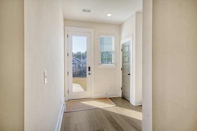 doorway featuring a wealth of natural light, visible vents, baseboards, and wood finished floors