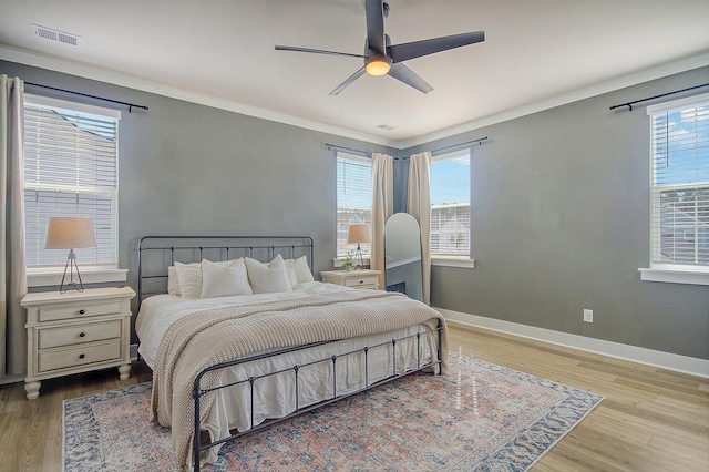 bedroom featuring visible vents, crown molding, baseboards, and wood finished floors