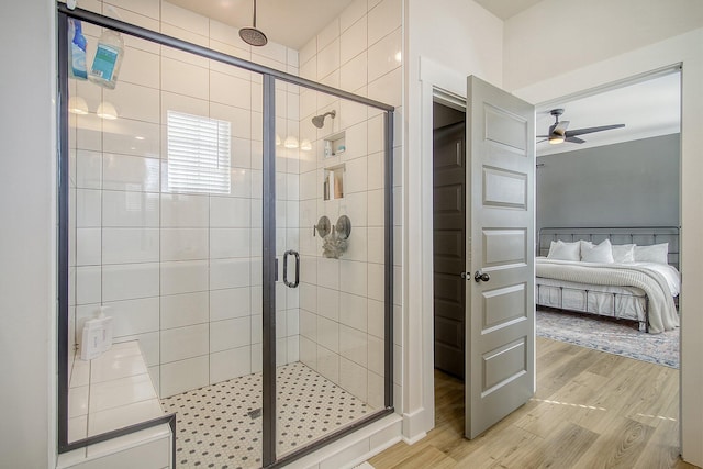 bathroom with connected bathroom, a stall shower, ceiling fan, and wood finished floors