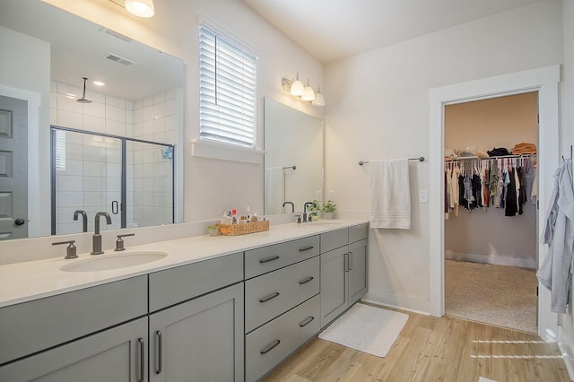 full bath featuring double vanity, visible vents, a stall shower, and a sink