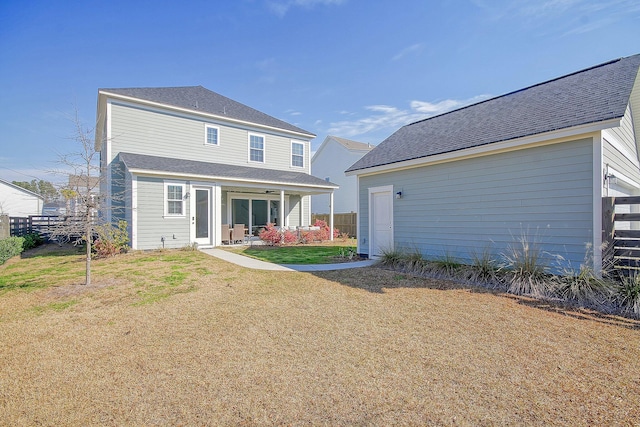 rear view of house featuring a lawn, fence, and roof with shingles