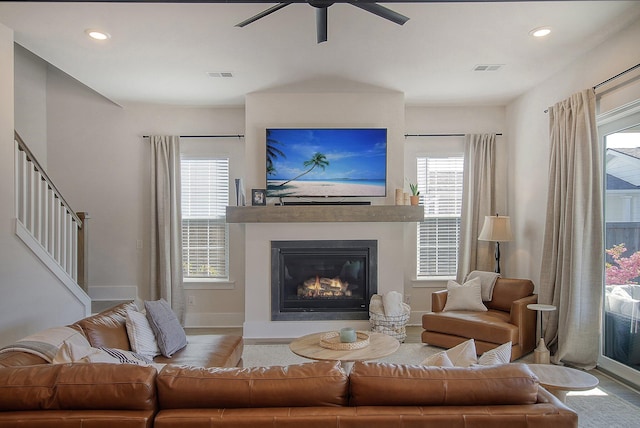 living room with recessed lighting, baseboards, a glass covered fireplace, and a ceiling fan