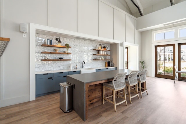 643 Blueway Ave, Summerville, SC 29486 - bar featuring light wood finished floors, high vaulted ceiling, wet bar, a sink, and backsplash