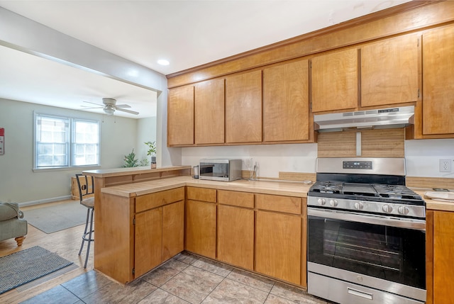 kitchen with kitchen peninsula, light tile patterned floors, stainless steel appliances, and ceiling fan