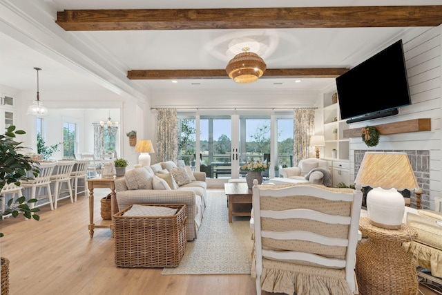 living room featuring a notable chandelier, beam ceiling, light hardwood / wood-style flooring, and french doors