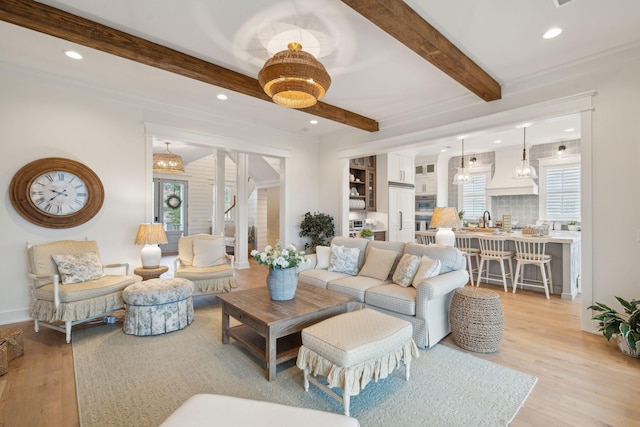 living room featuring sink, beam ceiling, and light hardwood / wood-style floors