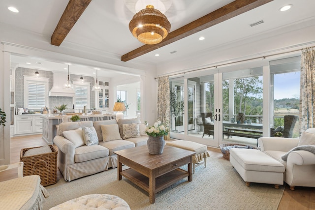 living room featuring beamed ceiling, sink, light hardwood / wood-style floors, and french doors