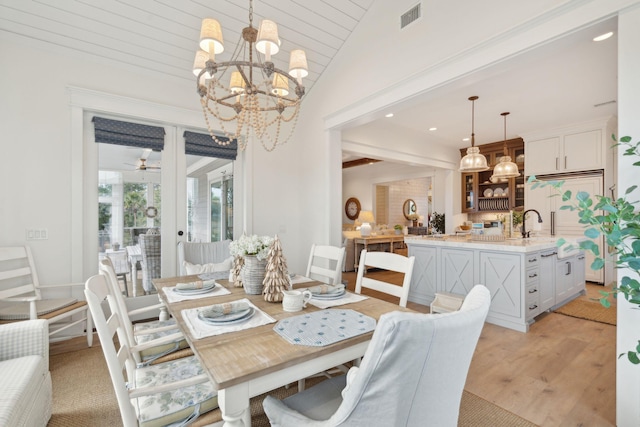 dining space featuring vaulted ceiling, ceiling fan with notable chandelier, and light hardwood / wood-style flooring