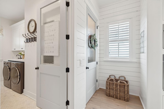 hallway featuring wood walls, independent washer and dryer, and light hardwood / wood-style floors