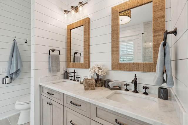 bathroom with vanity, toilet, and wood walls