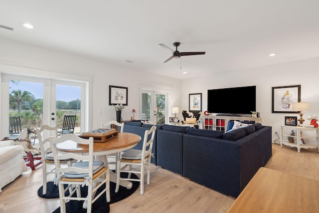 living room with light hardwood / wood-style flooring, ceiling fan, and french doors