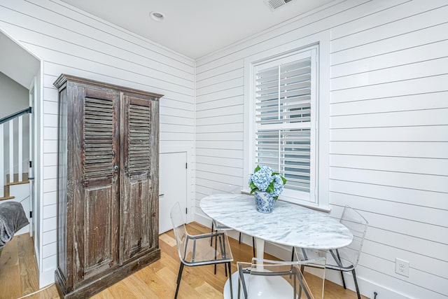 dining area with wooden walls and light hardwood / wood-style flooring