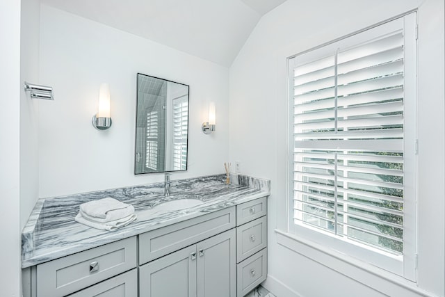 bathroom with vanity, lofted ceiling, and a healthy amount of sunlight